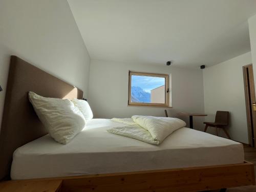 ein Bett mit weißen Laken und Kissen in einem Zimmer in der Unterkunft Residence Dilitz in Reschen