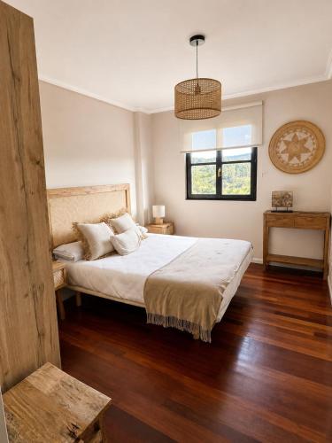 a bedroom with a large bed with wooden floors at Apartamento Guou in Comillas