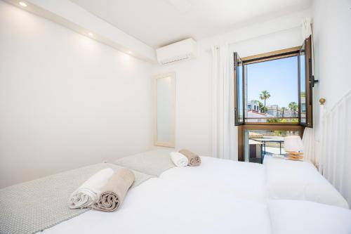 a white bedroom with a large bed and a window at Ana Playasol in Port d'Alcudia