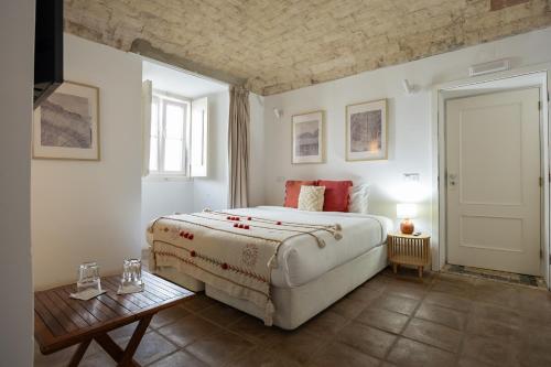 a bedroom with a large bed and a table at Solar de Arrayollos by PURUS in Arraiolos