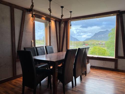 a dining room with a table and chairs and a large window at The Chess House Lofoten - Luxury Arctic Villa in Fredvang in Fredvang