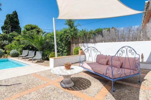 a pink couch sitting under an umbrella next to a pool at Villa Palma - Establiments by PriorityVillas in Palma de Mallorca