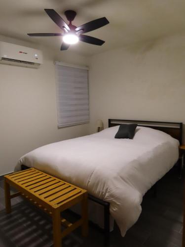 a bedroom with a bed with a ceiling fan and a bench at Loft-LunaRoja in Montemorelos