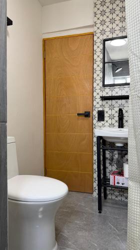 a bathroom with a toilet and a wooden door at Loft-LunaRoja in Montemorelos