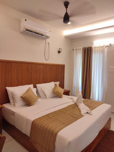 a bedroom with a large white bed with a fan at Aruvi on the cliff in Varkala