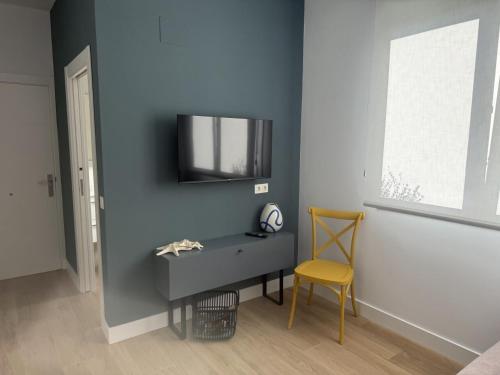 a room with a tv on a blue wall with a chair at Alojamientos Dima Costa in Laredo