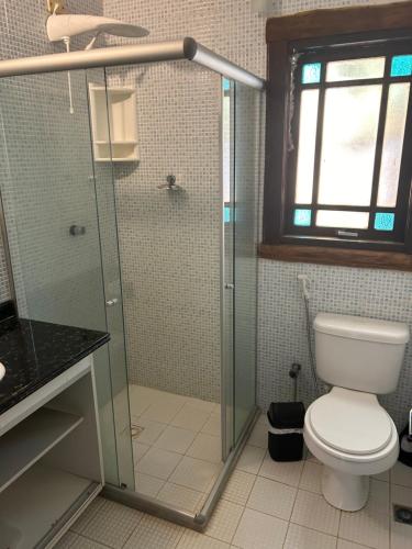 a bathroom with a toilet and a glass shower at Vilarejo do farol in Praia do Forte