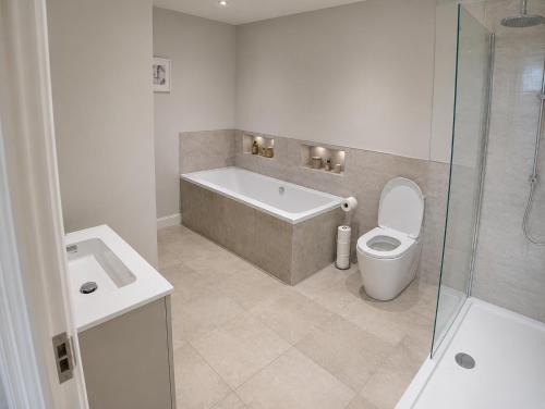 a bathroom with a tub and a toilet and a shower at Storm View in Castletown