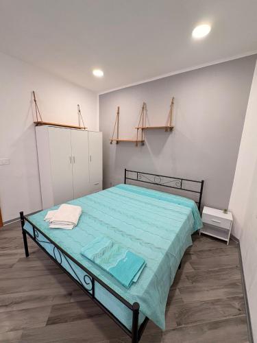 a bedroom with a bed with blue sheets and shelves at La casa del Borgo in Cetraro