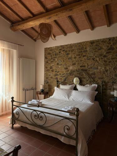a bedroom with a bed with a stone wall at Agriturismo Podere Santo Stefano in Cinigiano