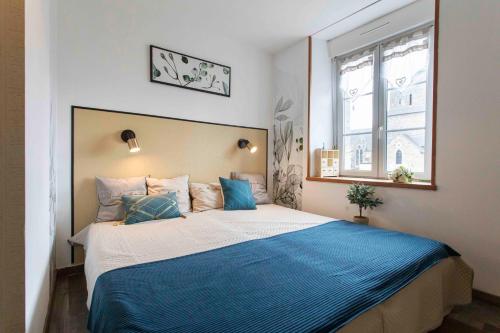 a bedroom with a large bed with a blue blanket at Maison de La Beslière meublé de tourisme 2 étoiles in Folligny