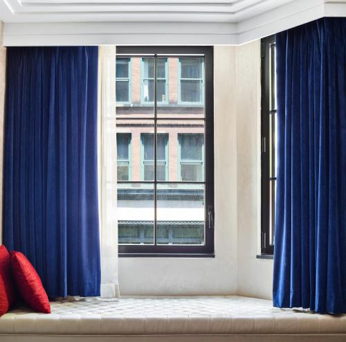 a living room with blue curtains and a window at Walker Hotel Greenwich Village in New York
