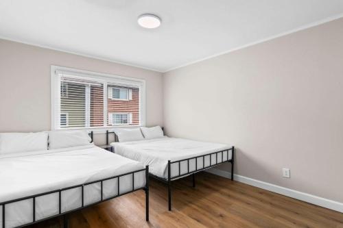 two beds in a white room with a window at Newly Renovated Unit in Central Spfld #203 in Springfield