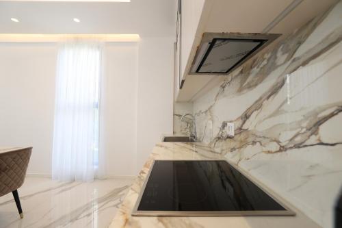 a kitchen with a marble counter top and a window at Palmera Dream Vila in Sarandë