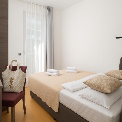 a bedroom with a bed with a chair and a window at Sunny resort apartment with pool access in Zadar