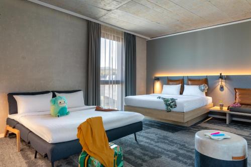 a hotel room with two beds and a couch at Moxy Outletcity Metzingen in Metzingen