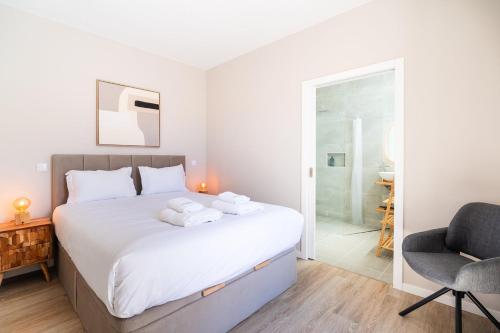 a bedroom with a large white bed and a chair at GuestReady – Steps from Sand • Champagne Pool in Machico