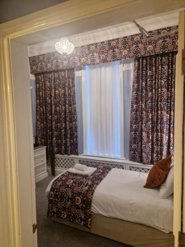 a bedroom with a bed and a window with curtains at St Margaret's Hotel in Oxford