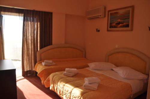 
two beds in a room with a large window at Hotel Drosia in Messini
