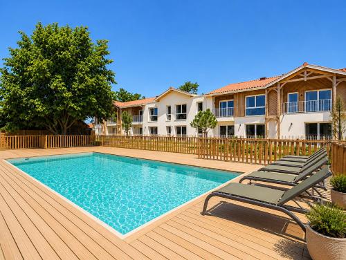 a swimming pool with two lounge chairs and a house at Le Mid-Length- studio pour 3 - piscine commune in Biscarrosse