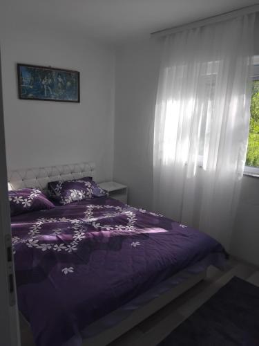 a bedroom with a purple bed and a window at Apartmani Nurka in Orašac