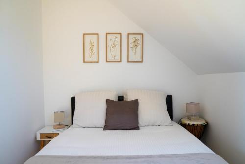 a bedroom with a white bed with three pictures on the wall at Chambre d'hôtes près du Château in Sully-sur-Loire