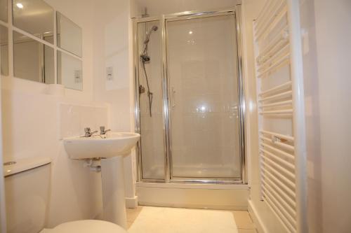 a white bathroom with a shower and a sink at Tideslea Riverview Apartment in Plumstead