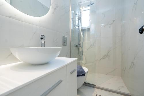 a white bathroom with a sink and a shower at Aspasia Studios in Lixouri