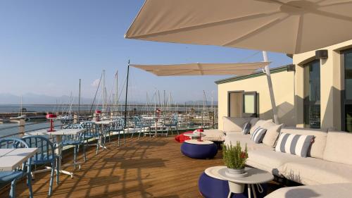 a deck with tables and chairs and umbrellas at Residence Hotel L'incanto Di Boccadarno in Marina di Pisa