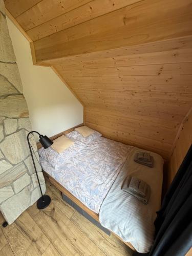 a small bed in a room with a wooden ceiling at Marcinówka - Górski Domek w Gorcach in Tylmanowa