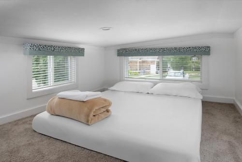 a white bedroom with a large white bed and two windows at Sun Outdoors Petoskey Bay Harbor in Petoskey