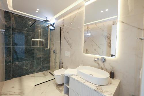a bathroom with a sink and a shower and a toilet at Palmera Prive Vila in Sarandë