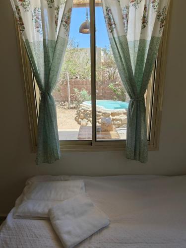 a bedroom with a window with a view of a pool at לנשום בצוקים in Zuqim