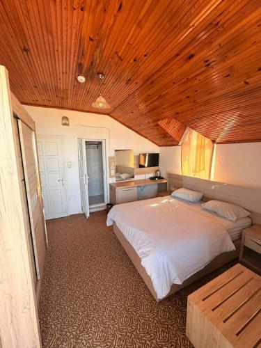 a bedroom with a large bed and a wooden ceiling at Divisey Pansiyon in Unye