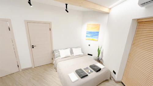 a white bedroom with a bed and a door at Beautiful Tinyhouse near the Beach in Lapmežciems