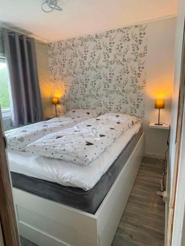 a bed in a bedroom with two lamps on the wall at Svolvær Minihouse in Kongsmarka