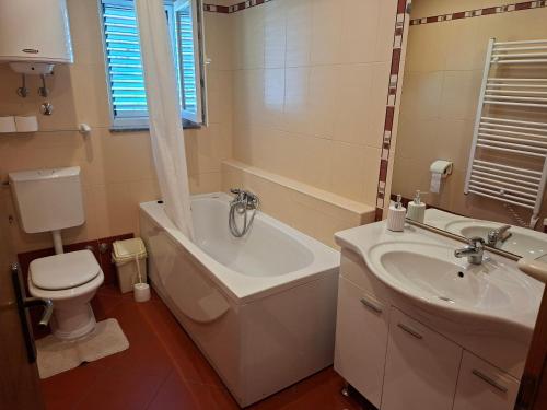 a bathroom with a tub and a toilet and a sink at Apartmani Dijana in Rab