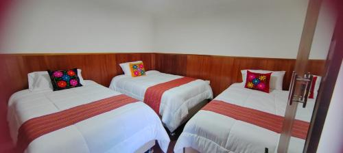 a room with three beds in a room at Pukari Hotel Cusco in Cusco