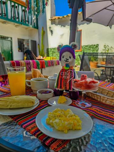 a table topped with plates of food and a teddy bear at Pukari Hotel Cusco in Cusco