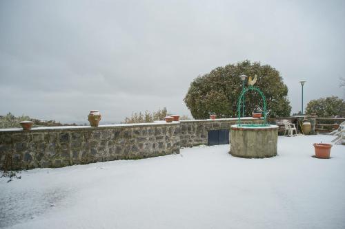 a snow covered yard with a stone wall and a playground at Etna Paradise locazioni brevi in Ragalna