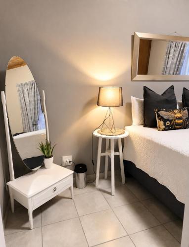 a bedroom with a bed and a table and a chair at Zhantique Guest House 2- Unit 11 in Boksburg