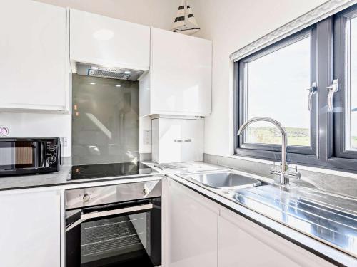 a white kitchen with a sink and a microwave at 1 Bed in Weymouth oc-82099 in Osmington