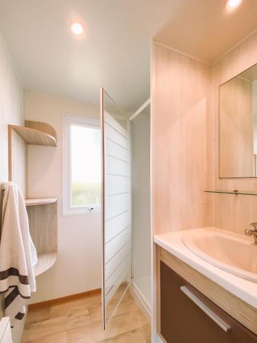 a bathroom with a sink and a tub and a window at Camping calme En Charente Maritime in Surgères