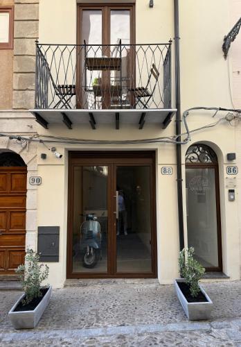 a front door of a building with a balcony and a motor scooter at Aria Suites Cefalù in Cefalù