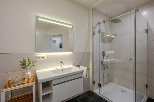 a white bathroom with a sink and a shower at Strandhaus Zingst Apartment 11 in Zingst