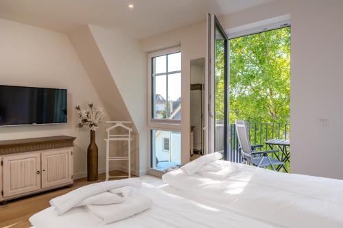 a bedroom with a bed and a tv and a balcony at Strandhaus Zingst Apartment 16 in Zingst