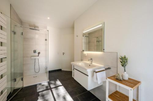 a white bathroom with a sink and a shower at Strandhaus Zingst Apartment 16 in Zingst
