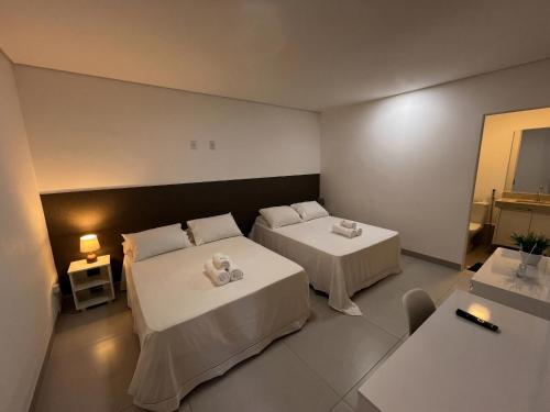 a hotel room with two beds and a table at Flamboyant Stay Rooms in Goiânia
