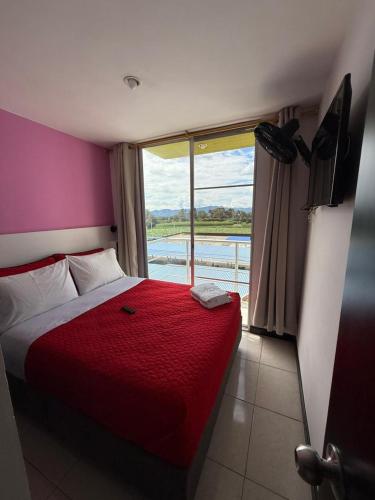 a bedroom with a red bed and a window at Apartahotel Paraíso Cafetero Guaduales del café 401B in Montenegro