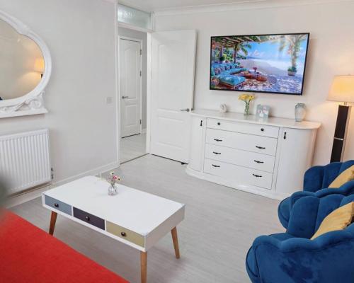a living room with a blue chair and a white dresser at Fully accessible bungalow by the Beach in Port Talbot